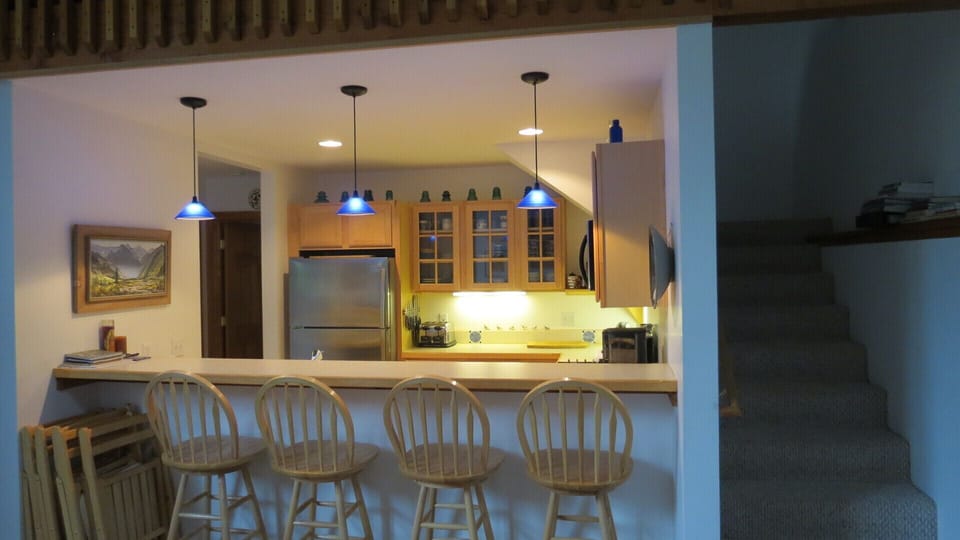 View of the kitchen from the living room with stairs to the loft.