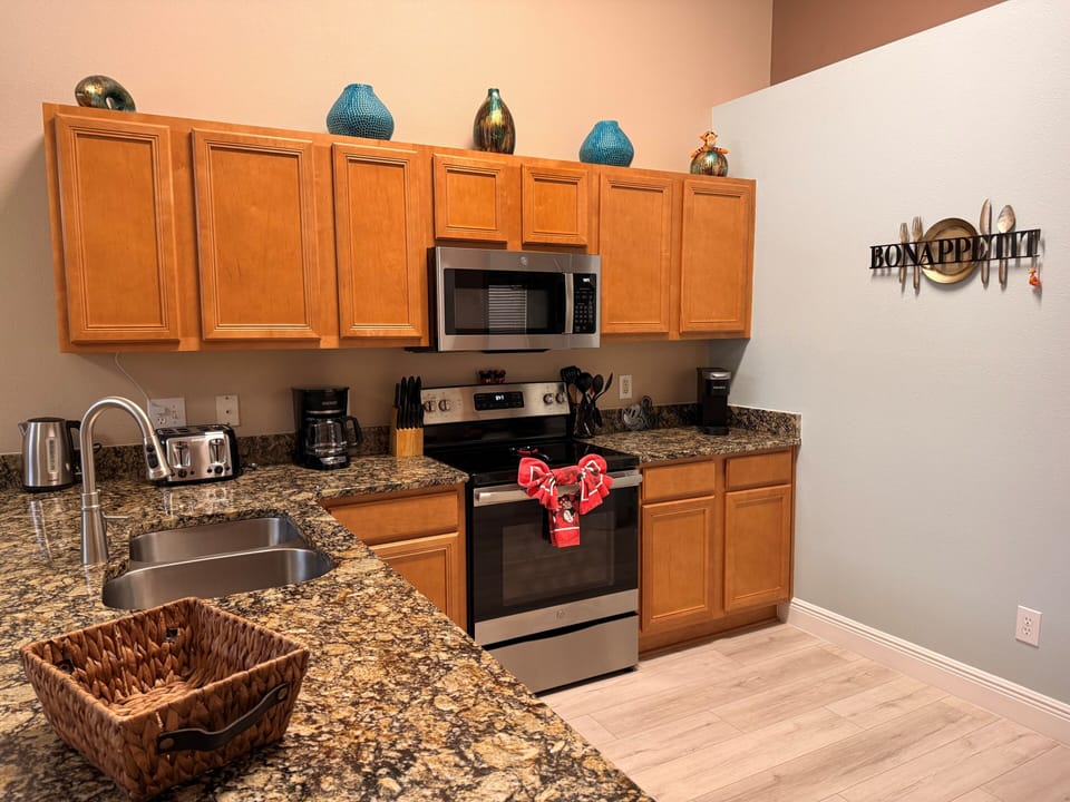 Kitchen with glass-top range, built in microwave, fan, under-cabinet lighting. 