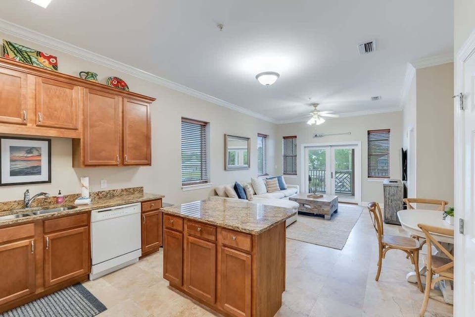 - Open concept design keeps everyone connected from the kitchen to the TV zone - Granite island, warm wood cabinets, and coastal art bring style and functionality - Whether you're sipping wine or prepping meals, it’s all done with ease and charm