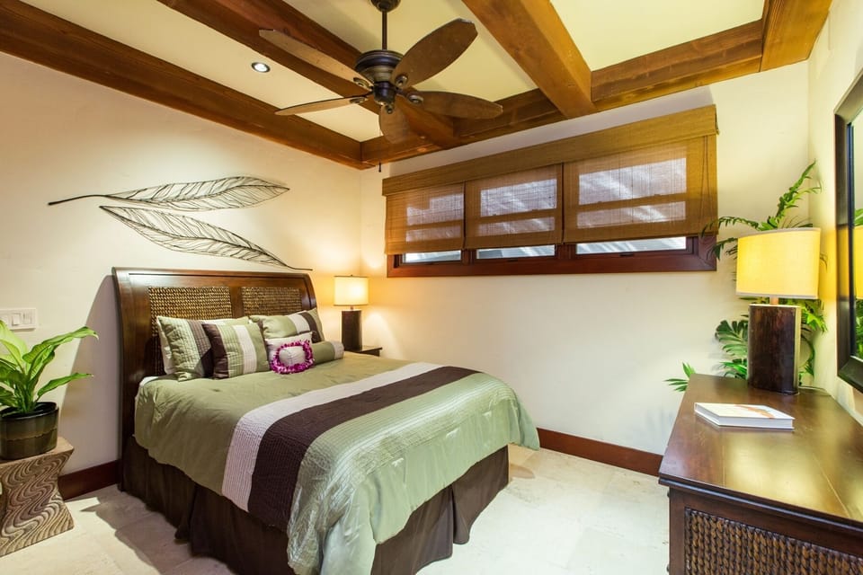 The guest cottage bedroom offers a peaceful setting with warm wood finishes and island-inspired design.