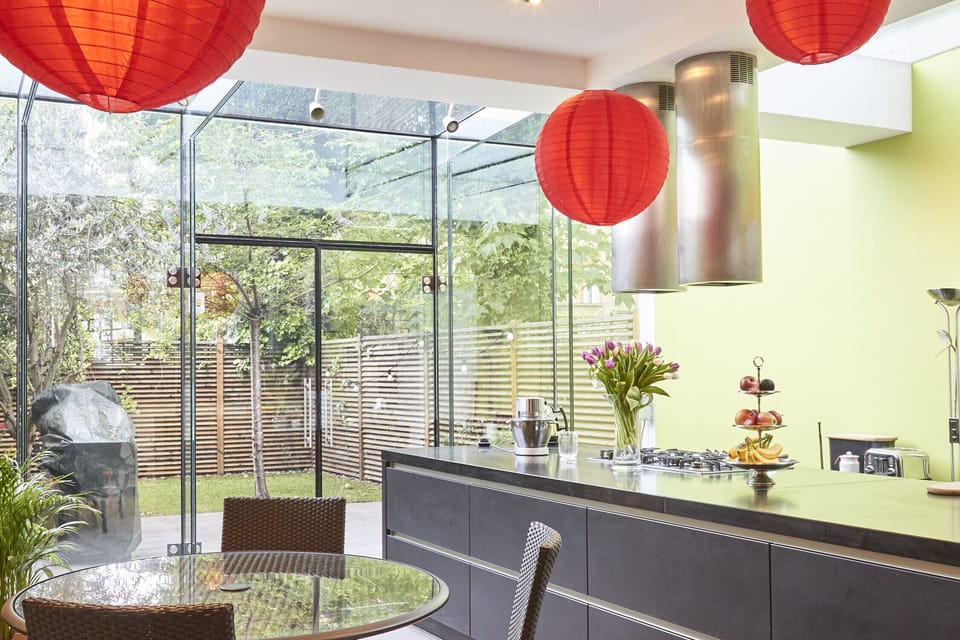 Modern kitchen with a conservatory opening onto a south-facing garden with grill