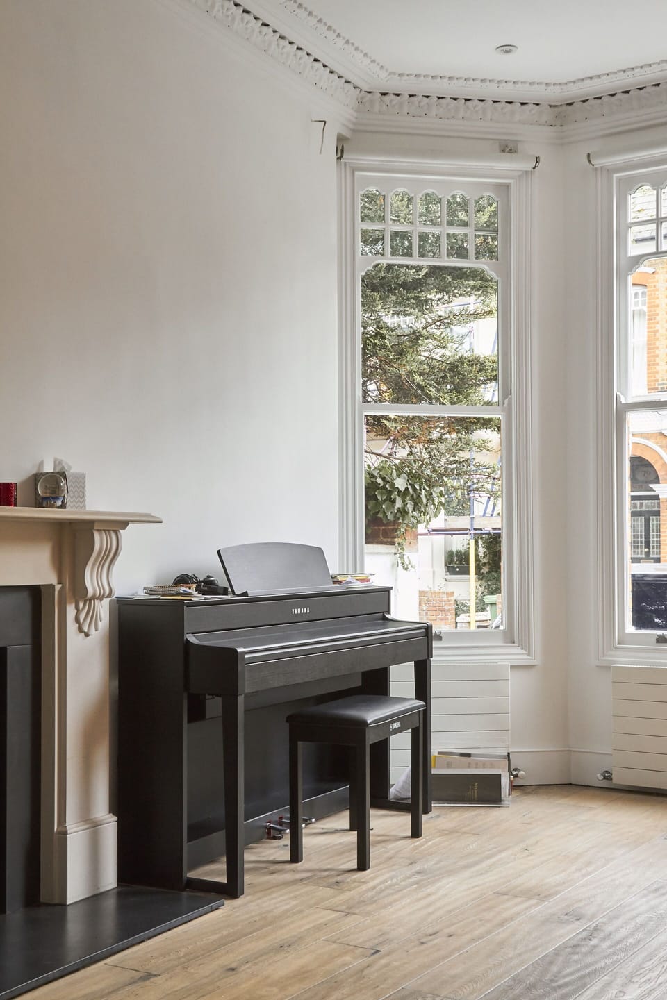 Living area with Yamaha electric piano and period bay windows. 