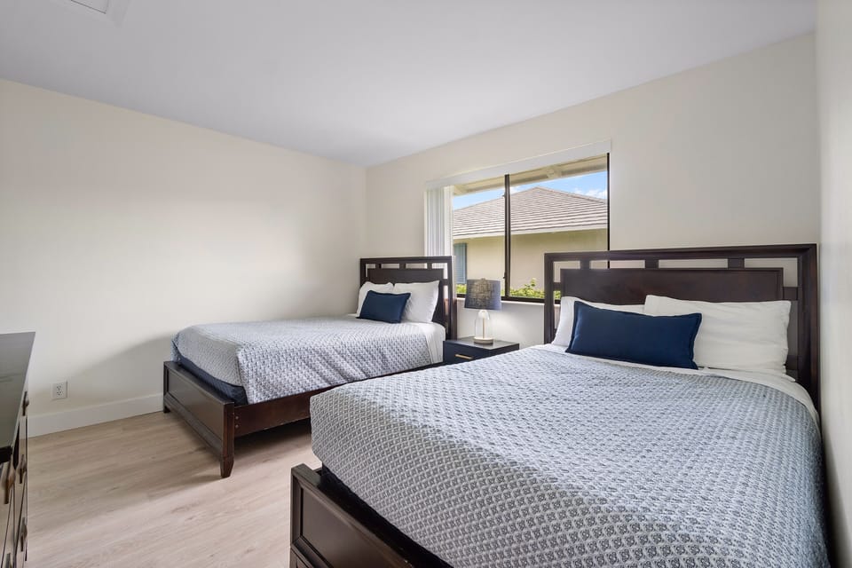 Guest bedroom with two double beds, 32-inch TV, and a walk-in closet.
