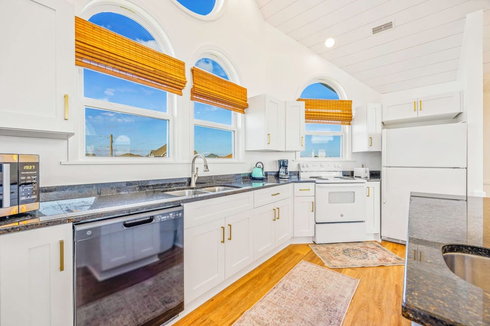 Your fully equipped kitchen features elegant arched windows with bamboo shades, granite countertops, and modern appliances for memorable meal preparations.