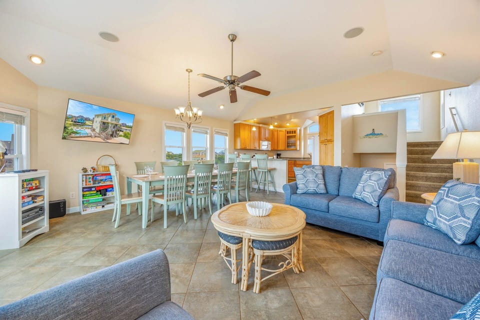 Stretch out in this inviting open-concept space where coastal-style comfort meets home. Your living and dining areas flow seamlessly together under vaulted ceilings, perfect for gathering after a day at the beach.