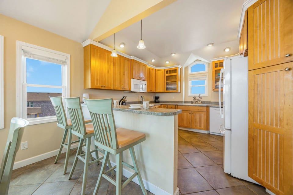 Gather around the breakfast bar in this bright, fully equipped kitchen and start your mornings with coffee and conversation. Warm wood cabinetry and ample counter space invite you to prepare meals together.