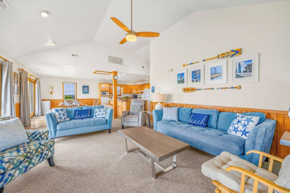 Relax in this inviting coastal living room with vaulted ceilings, comfortable seating, and beach-themed décor that welcomes you to unwind.