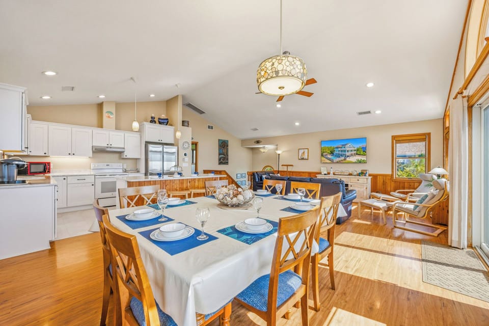 Gather your group around this spacious dining table, where the open-concept design lets laughter flow easily between cooking and conversation. Warm wood tones and coastal blue accents create a welcoming vibe perfect for memorable meals together.