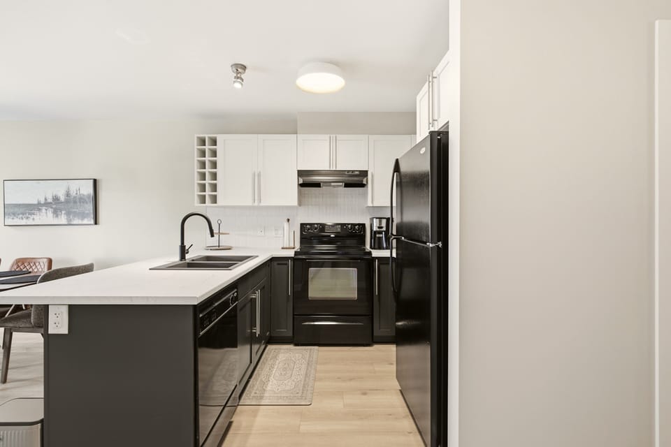 This kitchen has an electric stove, microwave, dishwasher, and full fridge.