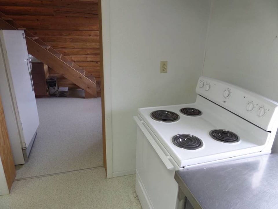 Stovetop/oven and refrigerator with stairs leading to loft