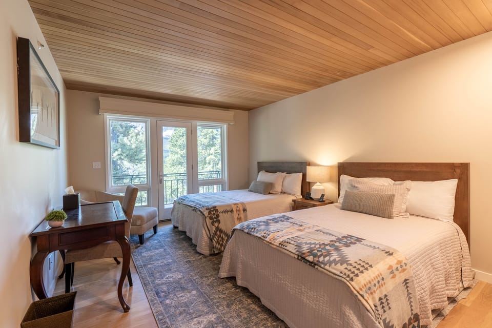 Double room with two double beds, attached bathroom, and access to the deck.