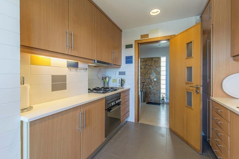 Modern galley kitchen with wooden cabinetry and gas range — Villa Foz, holiday villa in Sesimbra
