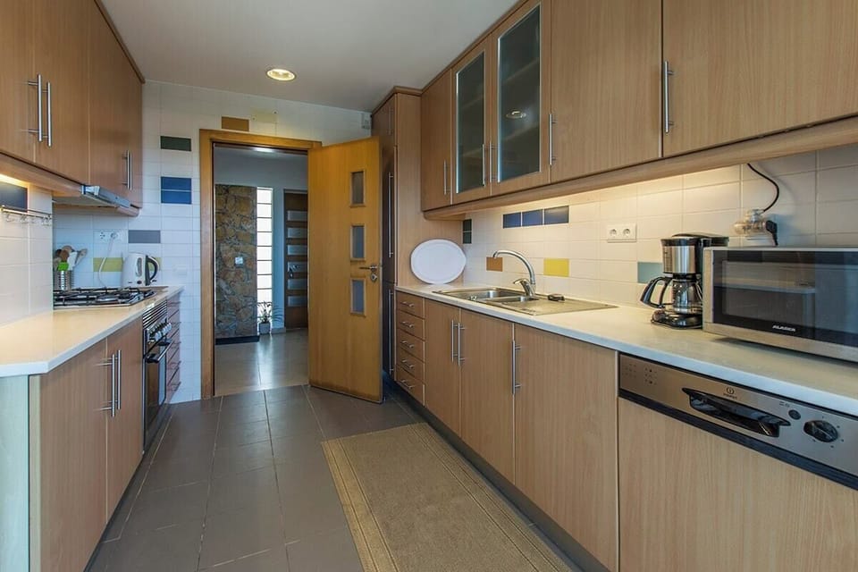 Modern galley kitchen with wood cabinetry and stainless steel appliances — Villa Foz, luxury holiday villa in Sesimbra