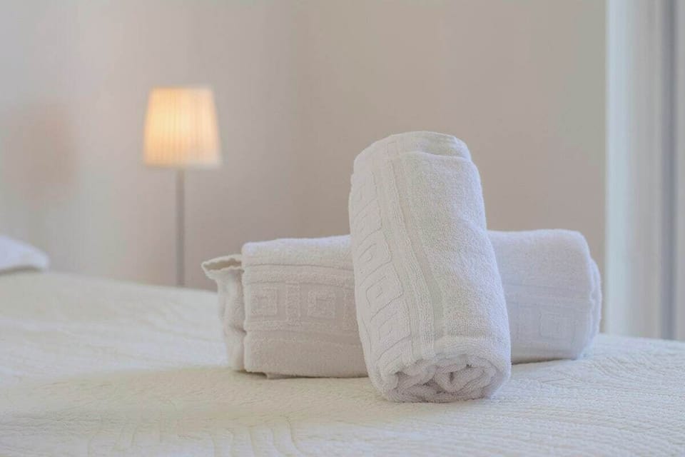 Rolled white towels on bed with ambient lamp — Villa Foz, luxury holiday villa in Sesimbra