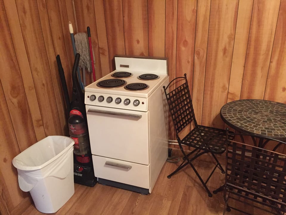 "Bunk House" Stove, cleaning tools, trash can, table, and chairs.