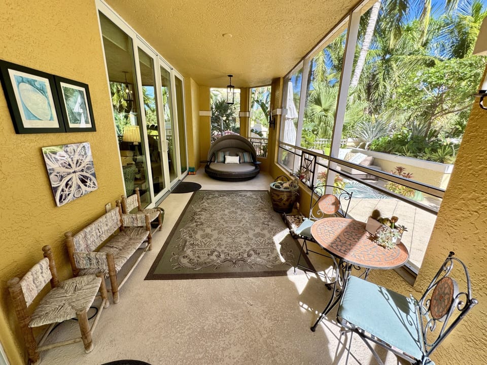 Lanai with lounge bed and cafe table and chairs, partial view of private patio.
