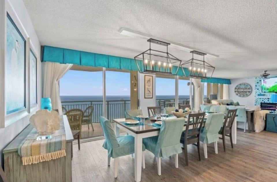 The large dining table in the open-concept living space seats a large family, and features a wall of sliding glass doors for incredible ocean views.