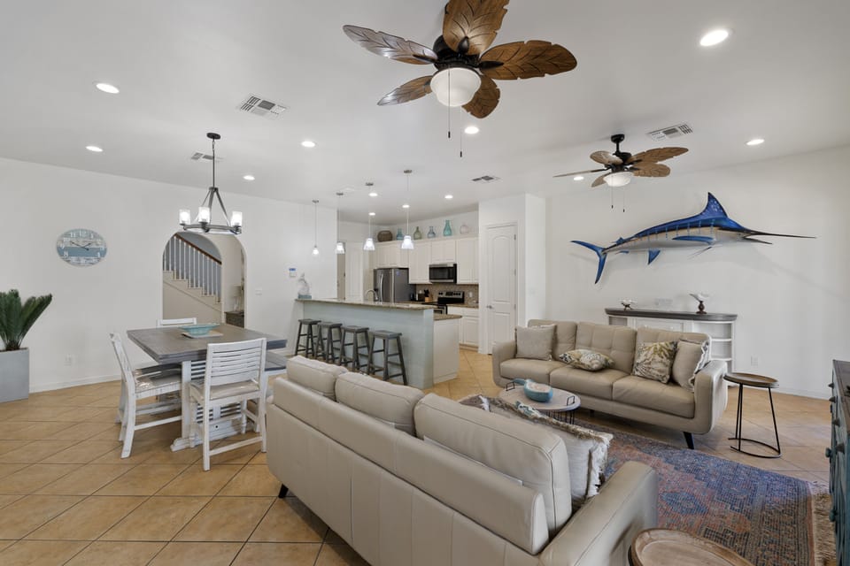 Bright open-concept living, dining, and kitchen area with chic coastal décor