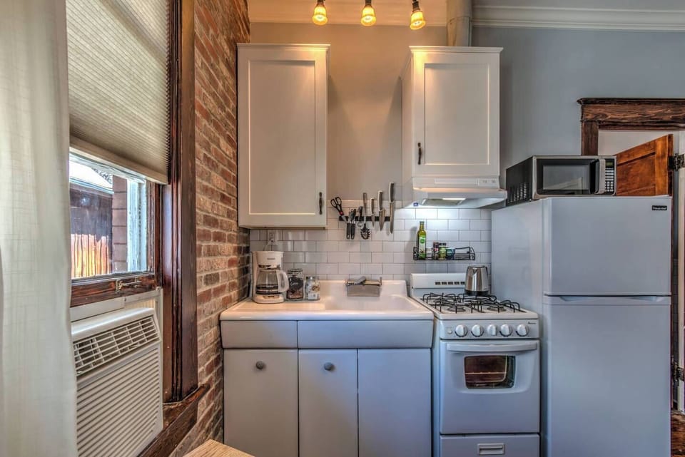 Compact kitchen with full stove, fridge, microwave, and coffee maker, everything you need for cooking at home or brewing your morning coffee.