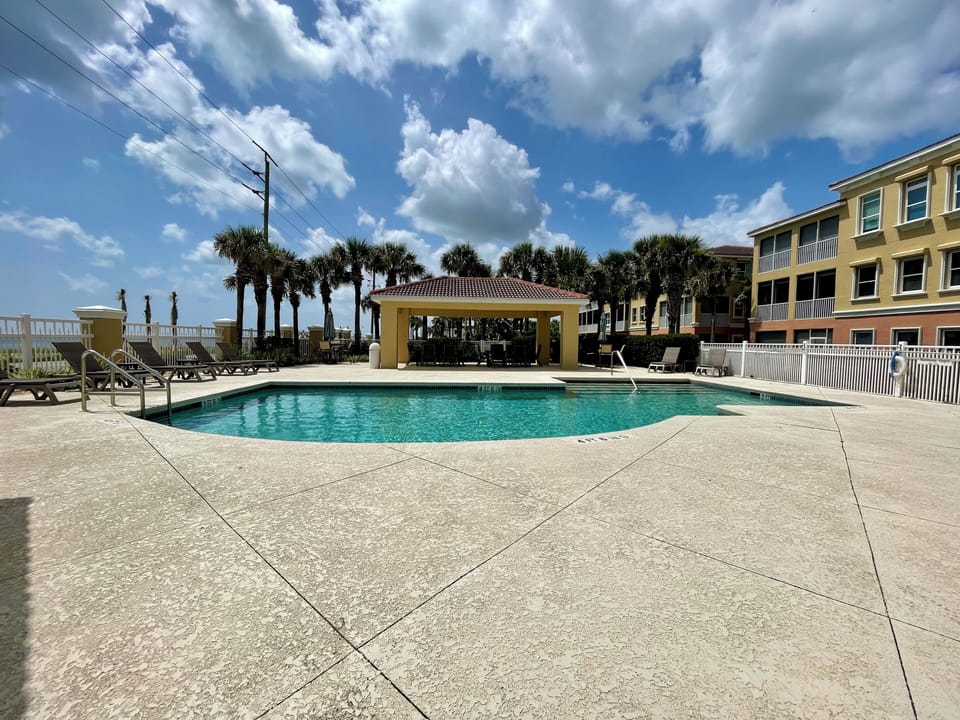 Sparkling pool with cabana, lounge chairs, and bathrooms