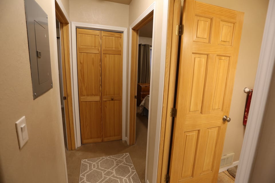 End of hallway with doors to both bedrooms and bathroom.