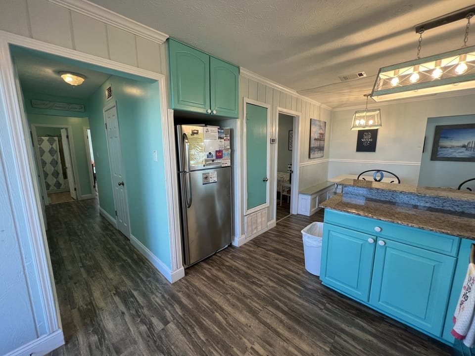 Your coastal-themed kitchen offers everything needed for memorable meals, with vibrant turquoise cabinets and granite countertops creating a cheerful cooking space.