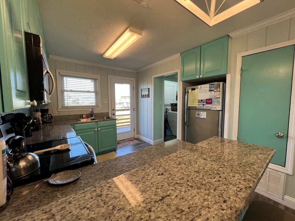 Your fully equipped kitchen features granite countertops, mint-green cabinets, and modern appliances for all your culinary needs.