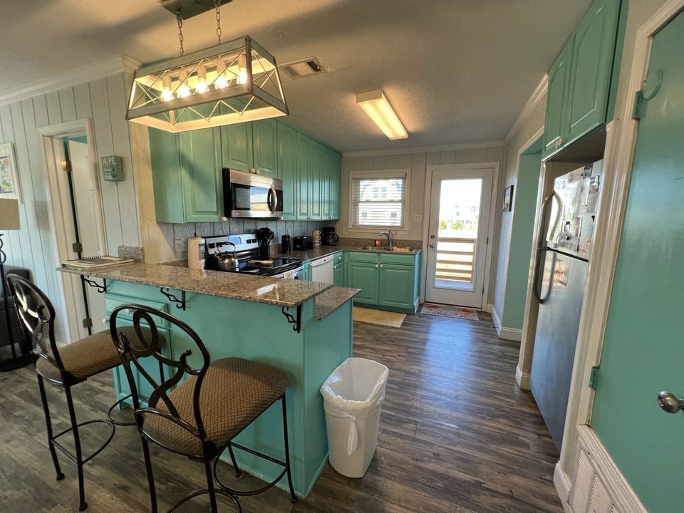 Your coastal-inspired kitchen awaits with charming mint cabinets, granite counters, and everything needed to create memorable meals together.