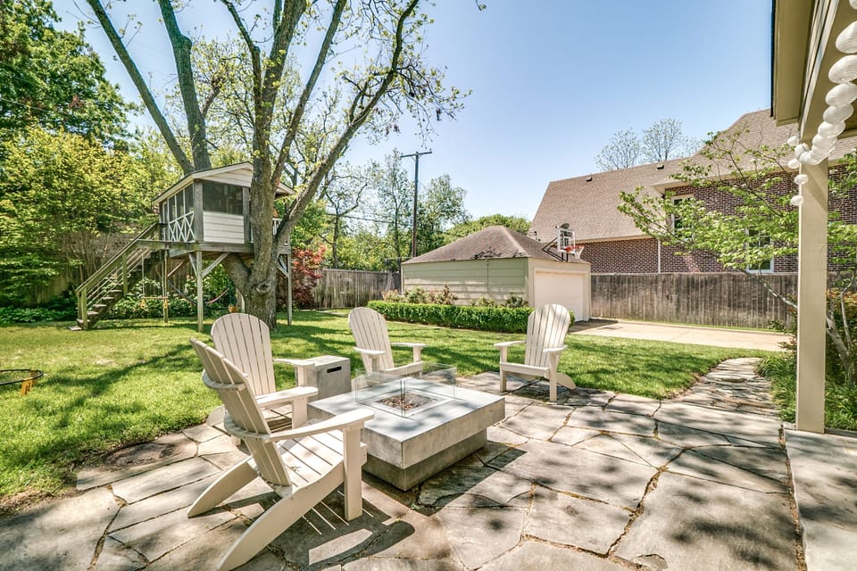 Large backyard with fire pit, treehouse, and trampoline