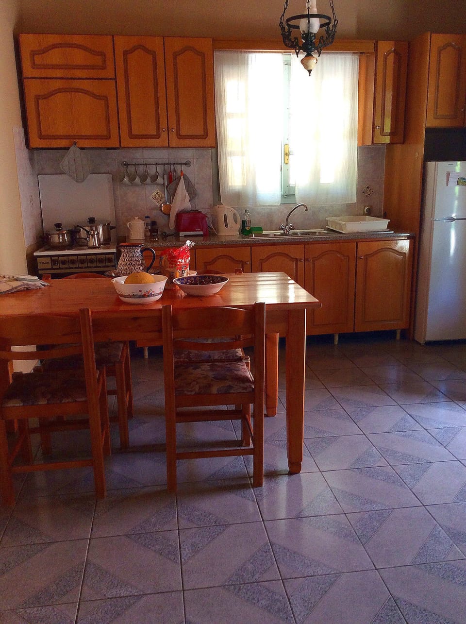 Kitchen zone offers dining table, refrigerator, stove, sink. Bungalow Kefalonia