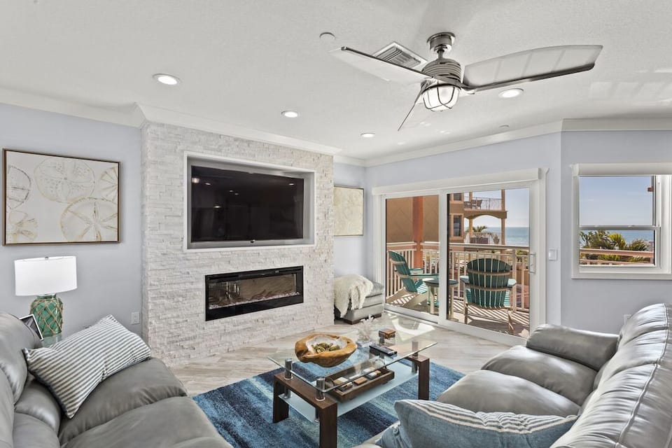 Living room w/modern firelplace, balcony & view of pool below & Gulf of Mexico. 