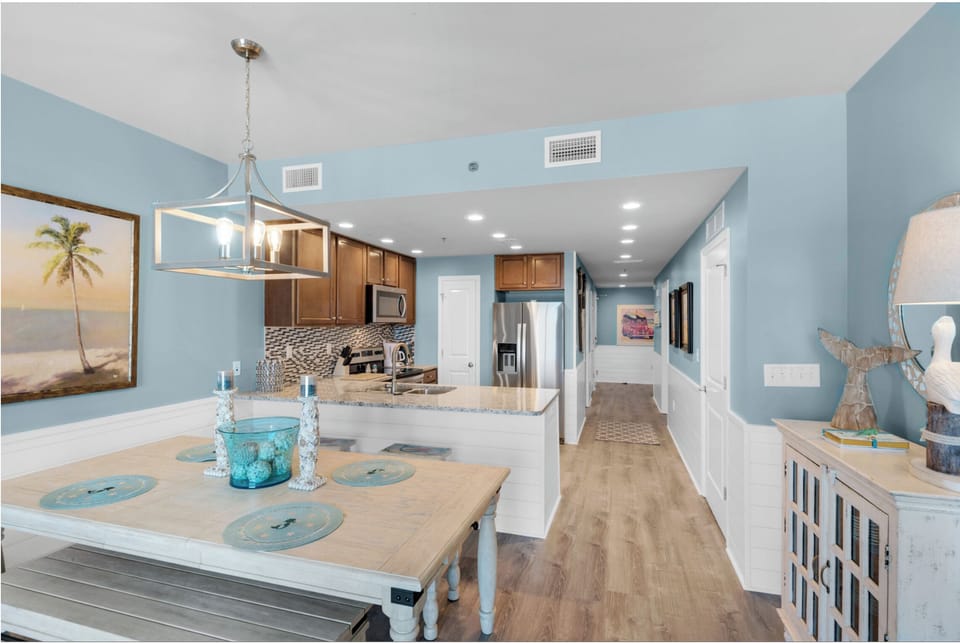 Your coastal-themed kitchen and dining area create the perfect space for gathering, with ocean-blue walls and beachy decor setting a relaxing vacation mood.