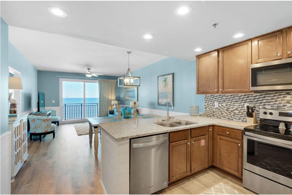Your fully equipped kitchen flows seamlessly into the living area, where ocean views through floor-to-ceiling windows create the perfect backdrop for cooking and relaxing.