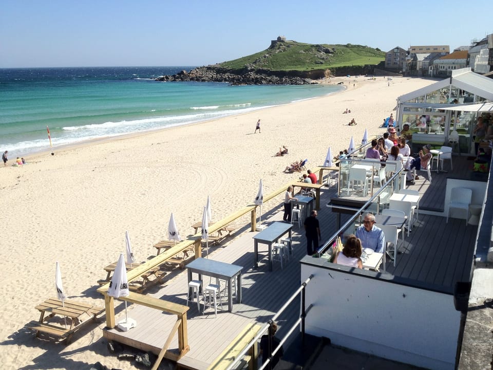 Porthmeor Beach with surf school, cafe and bakery. We walk here in our wetsuits!