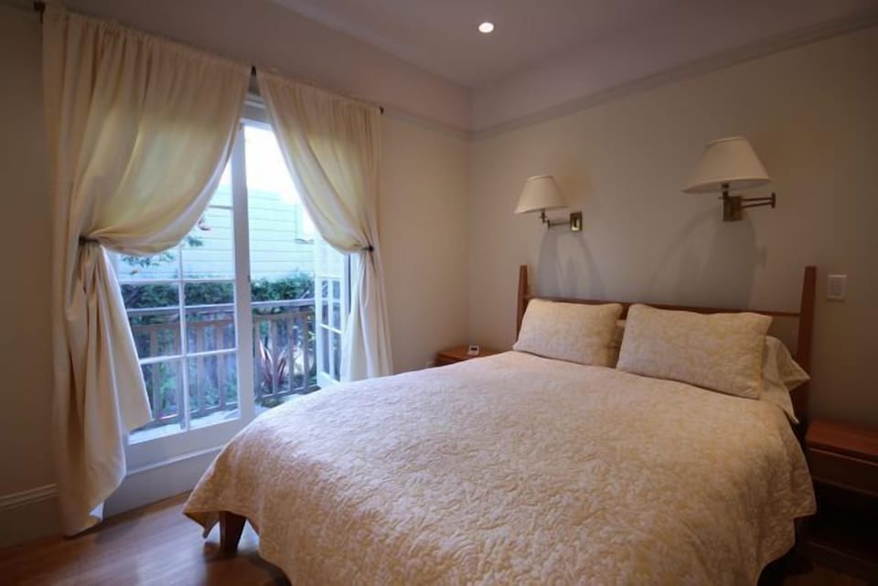 Charming bedroom with French doors and balcony overlooking garden.