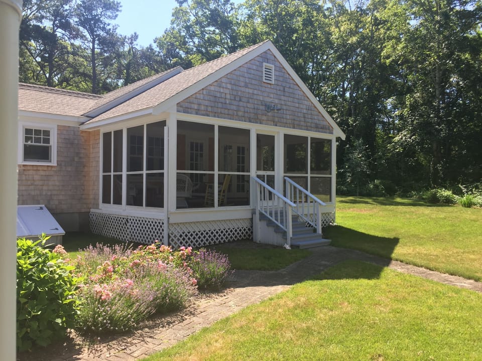 Brick walk leads from driveway to the screened porch overlooking private yard.