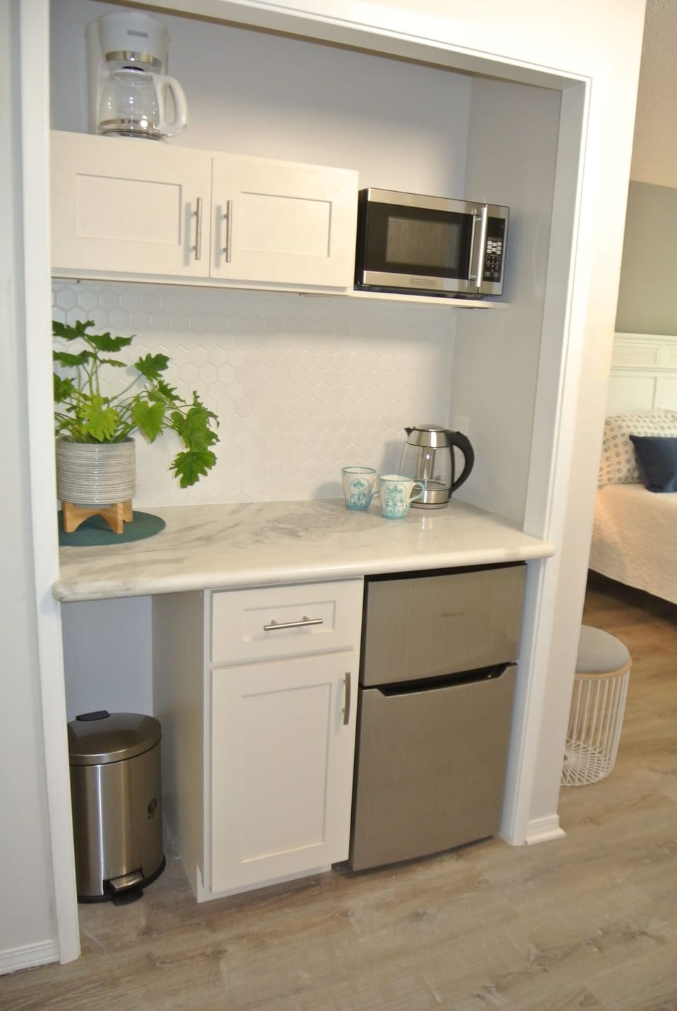 Bar area with fridge, microwave, electric tea kettle, coffee maker and dishes.