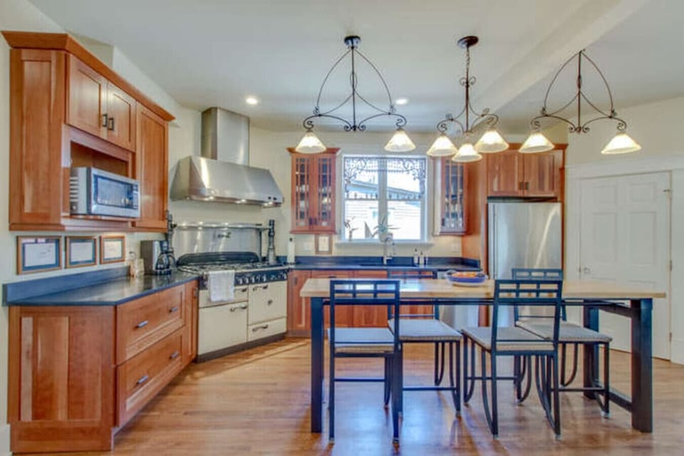 Kitchen with warm wooden cabinetry, stainless appliances, granite counters, and bar stools