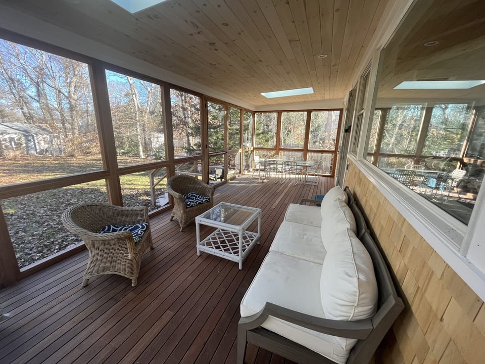 Screened-in back porch with seating and dining table facing backyard