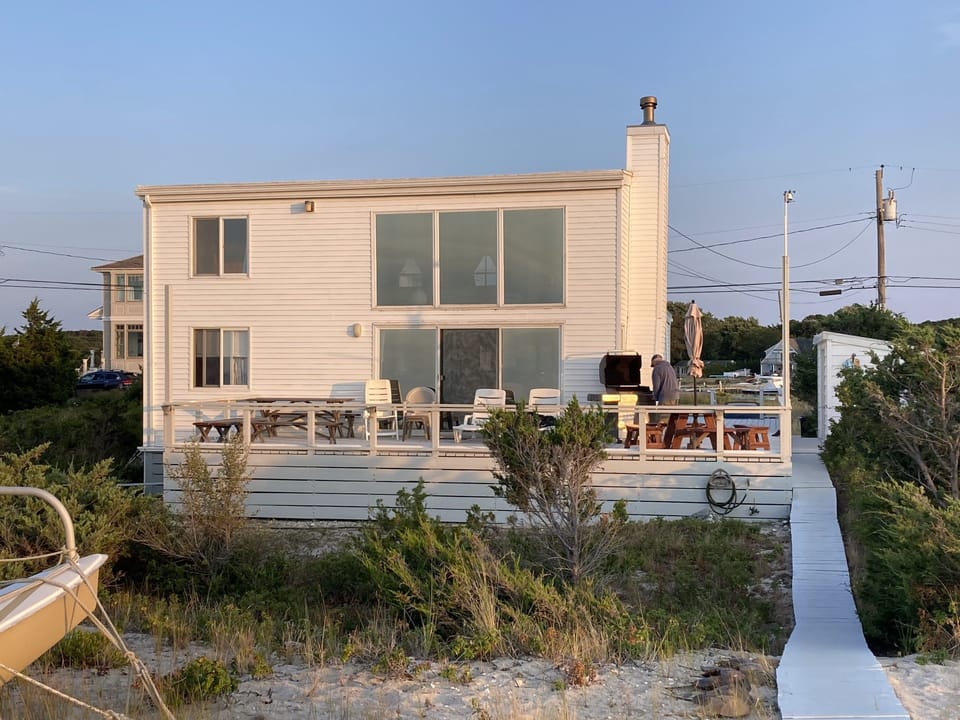 House on Peconic Bay beach. Tables, chaise lounges, chairs and  grill on deck
