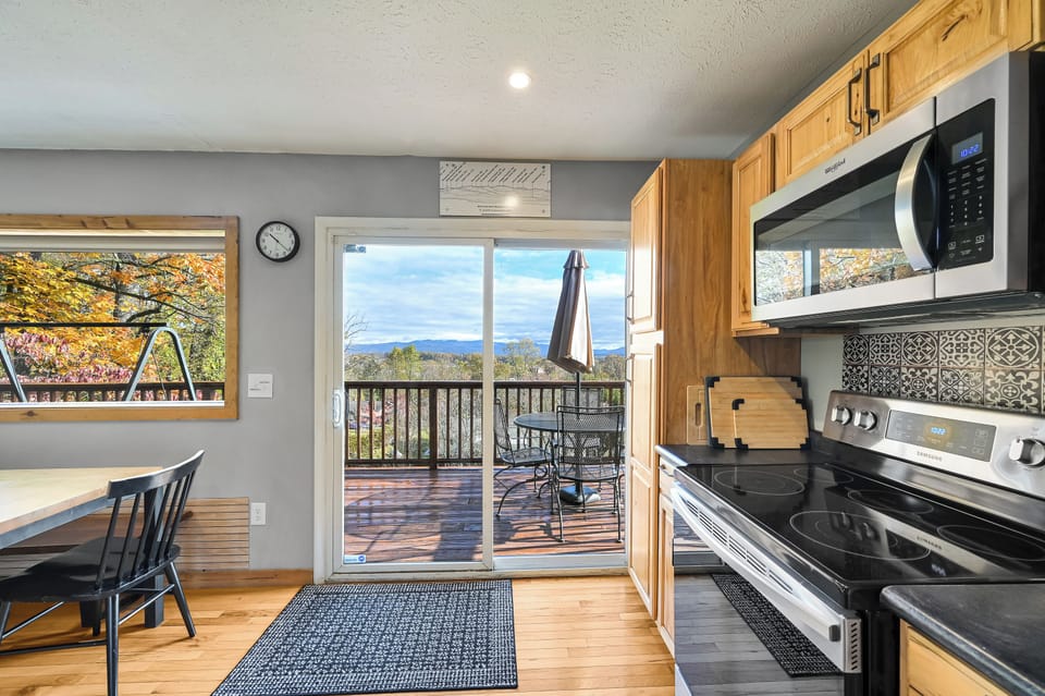 Door from kitchen out to deck and dining table with umbrella