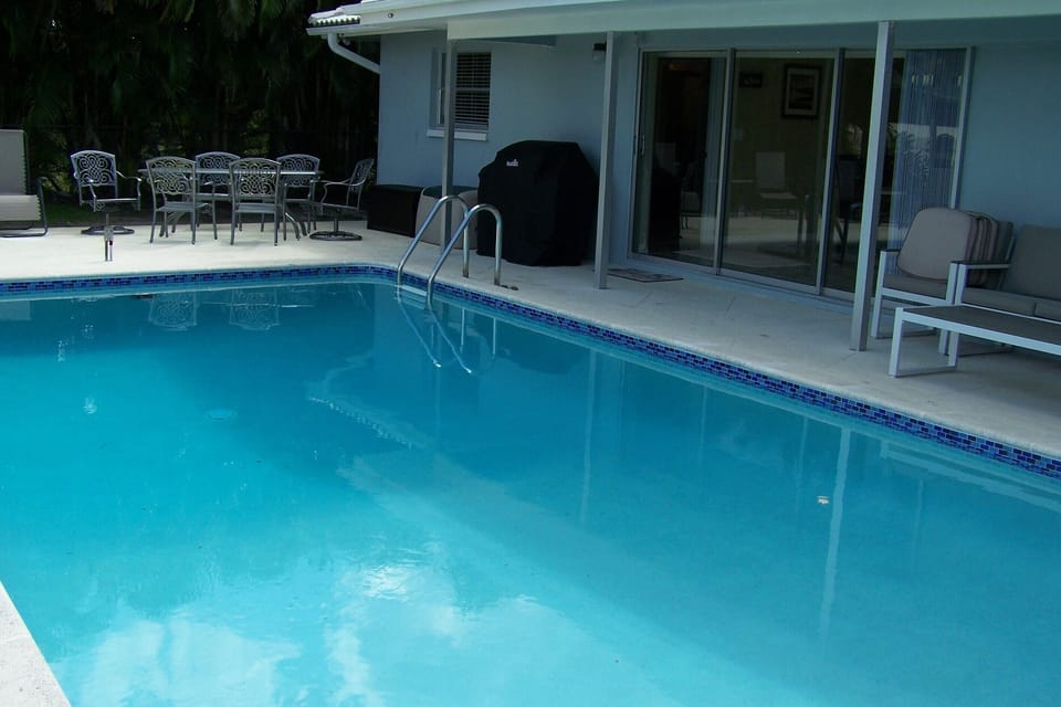The newly renovated pool with the grill and dining table and chairs in the backg