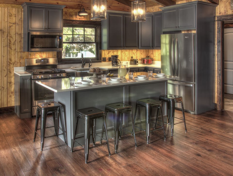 Main level kitchen, featuring stone counterops, island seating, and wine fridge