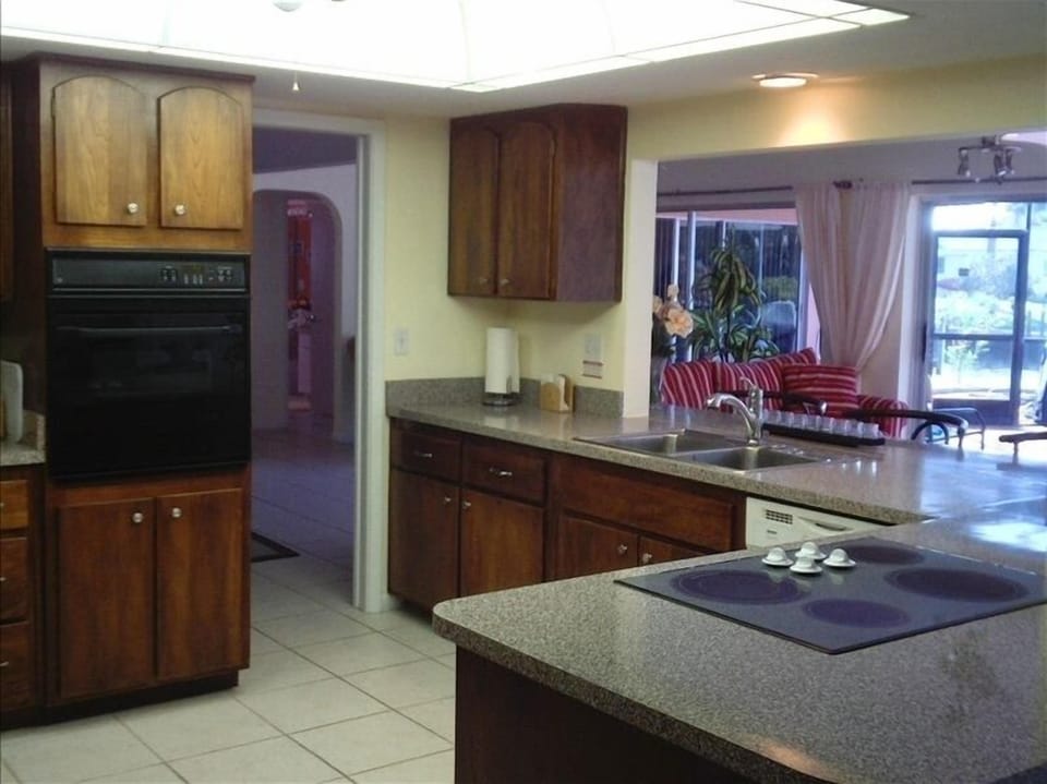 Well equipped kitchen opens to sun room and views of the pool deck