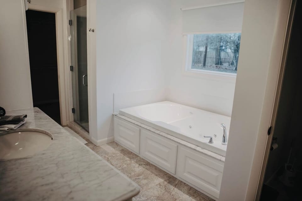 Master bathoom showing one of two sinks, walk in shower, tub, and toilet enclosure