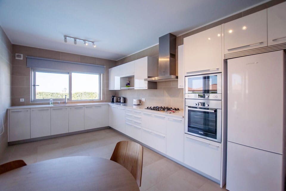 Modern white kitchen with gas cooktop and integrated appliances — Villa del Rey III, luxury holiday villa in Óbidos