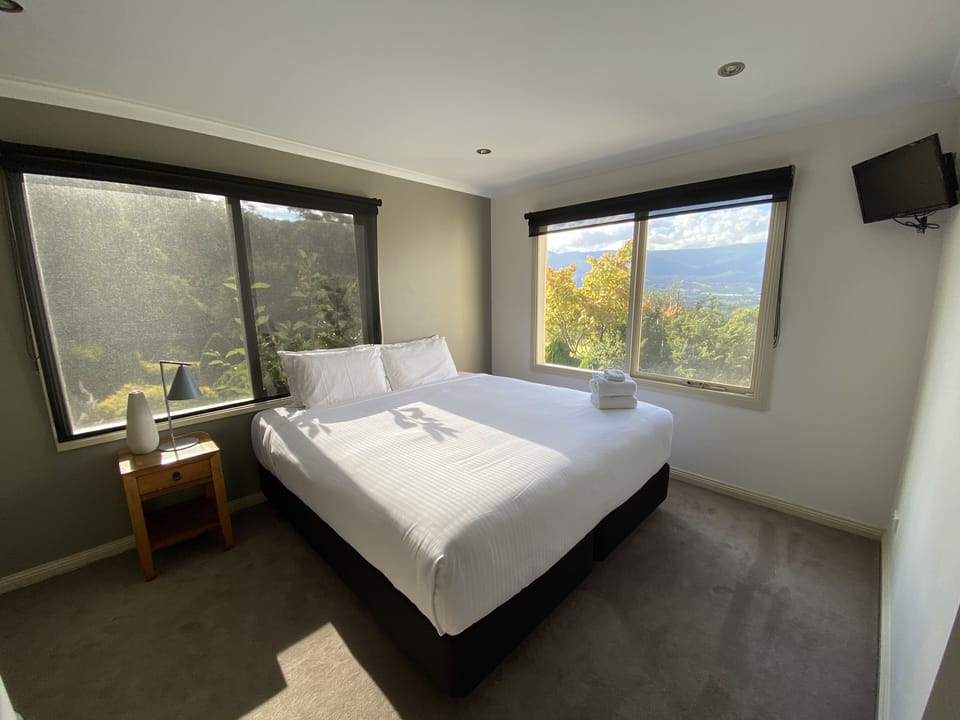 Bedroom 1 with views to Mt Donna Buang & the pool area. Bed can be split to twin