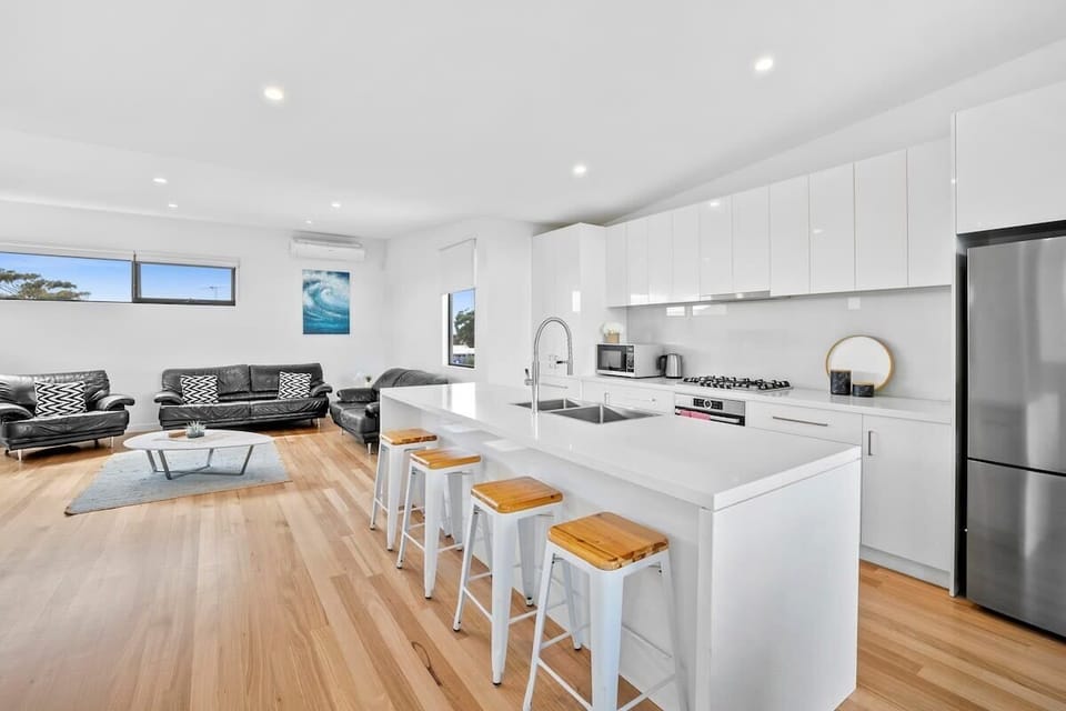 The upstairs living area features a fully equipped kitchen, dining area, and lounge with high ceilings and beautiful timber floors