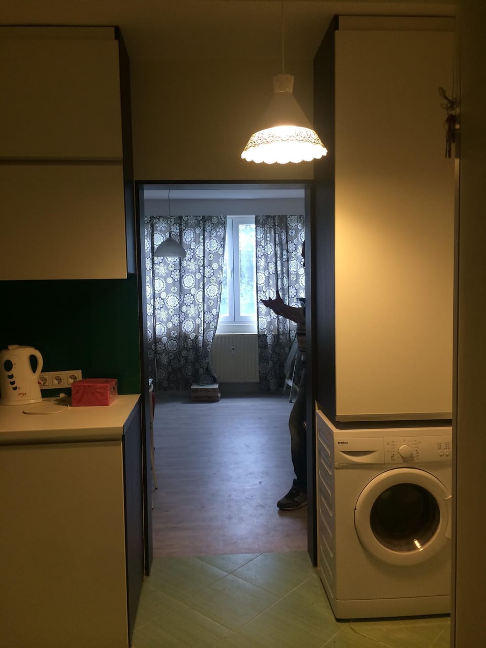 Washing machine. Cleaning supplies are stored in shelf above washing machine.