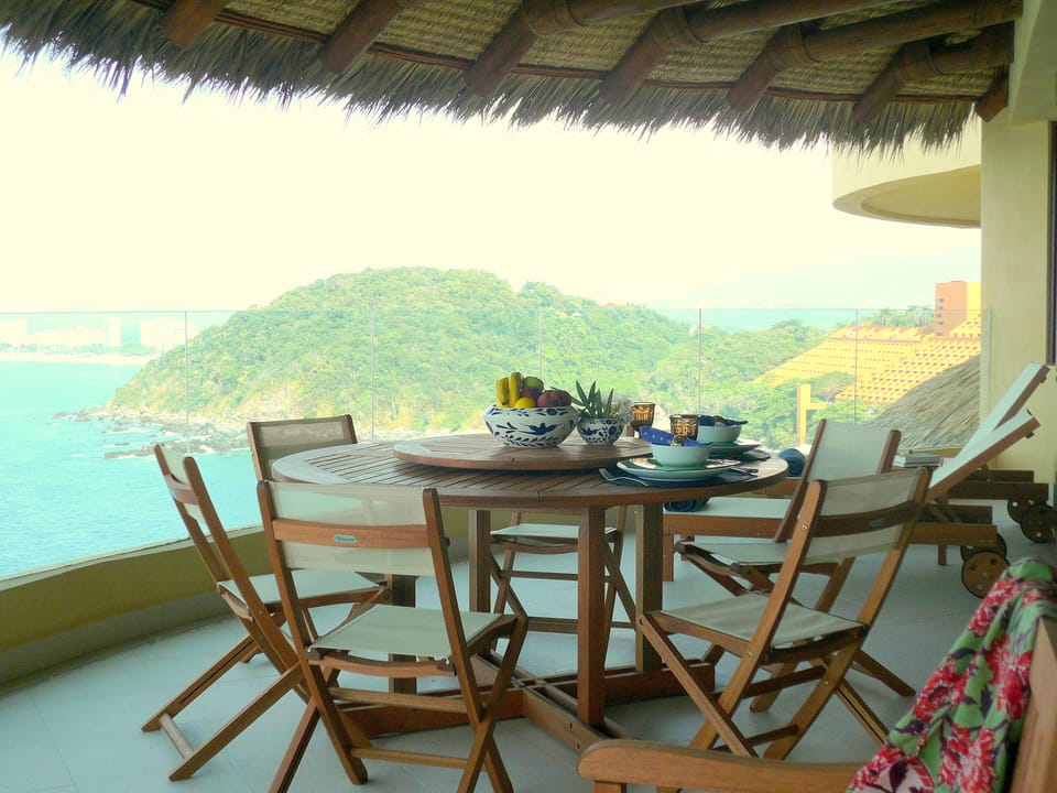 Terrace under detailed palapa, with dining table,lounge chairs and grill